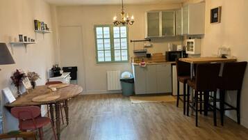 A compact kitchen with a dining area, wooden flooring, and a chandelier.