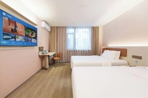 Quarto de hotel com duas camas, uma escrivaninha, uma cadeira, uma televisão e uma janela com cortinas.