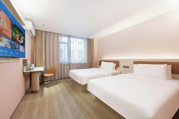 Quarto de hotel com duas camas, uma escrivaninha, uma cadeira e uma janela grande com cortinas.