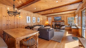 L’intérieur d’un chalet chaleureux, avec une table à manger en bois, un canapé et une cheminée.
