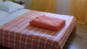 Een bed met een geruit sprei en een roze deken.