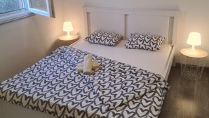 A bedroom with a bed, two bedside lamps, and heart-patterned bedding. - Apartments Rubbi - Two Bedroom Apartment with Terrace (Vrsi)