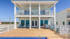 A two-story building with a wooden deck, a pool, and outdoor seating. - Beachfront House with Pool! 6 BR/6.5 Beachfront Paradise! (Gulf Shores)