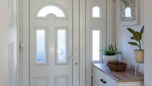 A white door with arched windows and a small basket on a wooden console table.