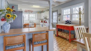 A kitchen with a central island, wooden chairs, a red table, and a hexagonal tiled floor. - Walk to Beach, Stunning Sunsets (Southampton)