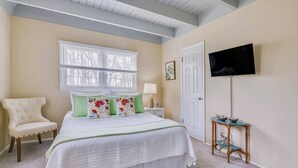 A bedroom with a bed, a chair, a nightstand, a television, and a window. - Walk to Beach, Stunning Sunsets (Southampton)
