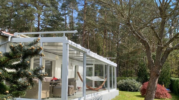 A modern house with a glass-enclosed porch, a dining area, and a hammock. - Ferienhaus in Herzwolde für 4+2 Personen (Wokuhl-Dabelow)