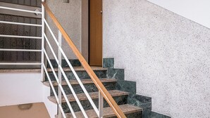 A staircase with a wooden handrail and white balusters, leading to a door with a metal handle. - Appartamento Bernini in zona Sant'Orsola by Wonderful Italy (Bologna)