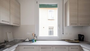 A modern kitchen with light wood cabinets, a stainless steel sink, and a window with a view of the street. - Appartamento Bernini in zona Sant'Orsola by Wonderful Italy (Bologna)