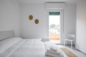 Une chambre moderne avec un grand lit, une chaise et une vue sur l’extérieur.