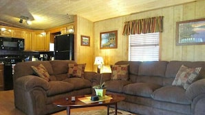 A cozy living room with two sofas, a coffee table, and a kitchen in the background.