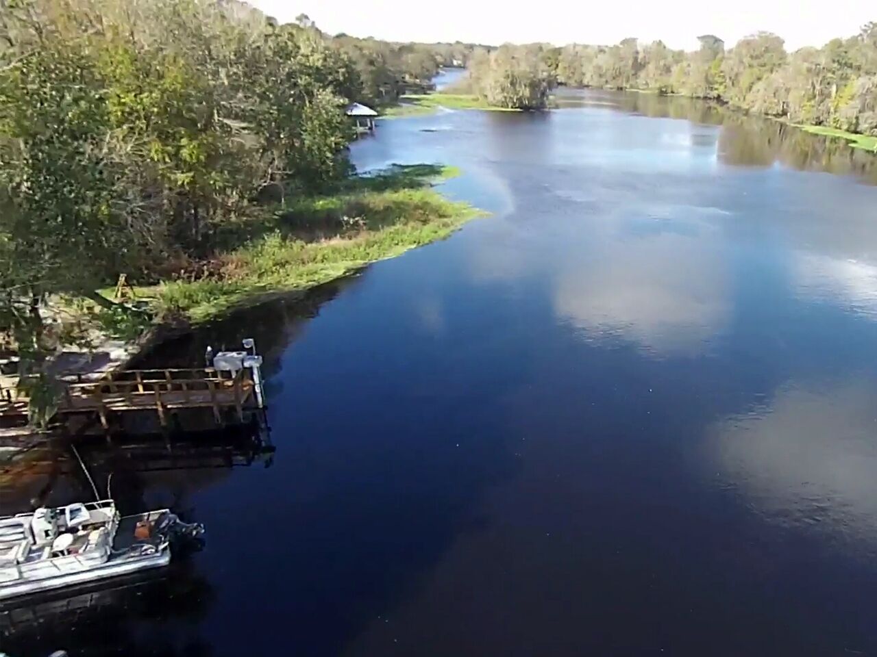 A river with a dock and a small building on the left.