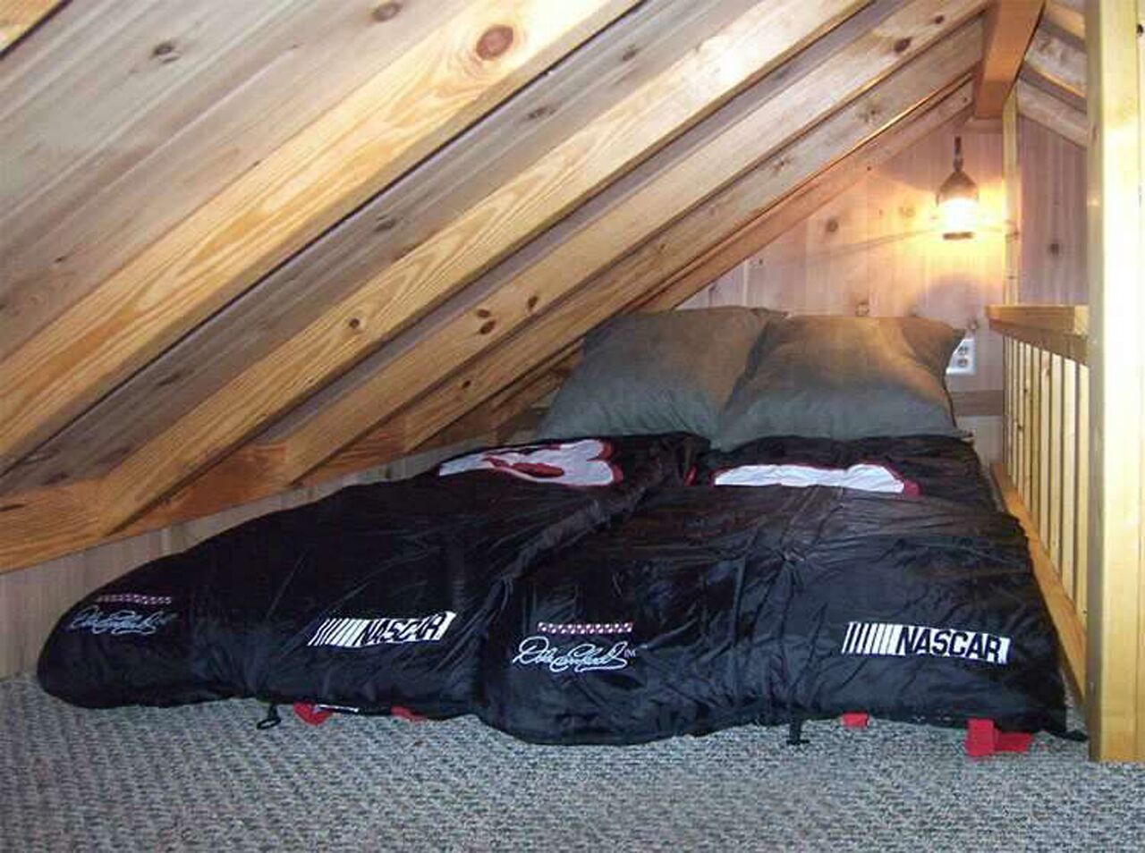 A bedroom with a sloped ceiling, a bed with a black cover, and a wooden headboard.