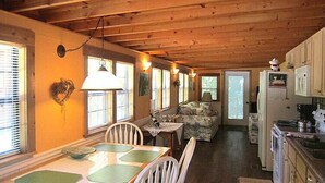 A cozy cabin interior with a dining area, kitchen, and living space. - Cozy Cabin in riverfront resort (Inverness)
