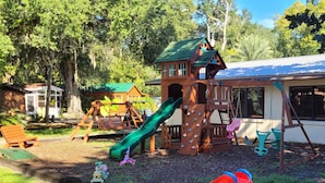 A playground with a slide, swings, and a climbing structure. - Cozy Cabin in riverfront resort (Inverness)