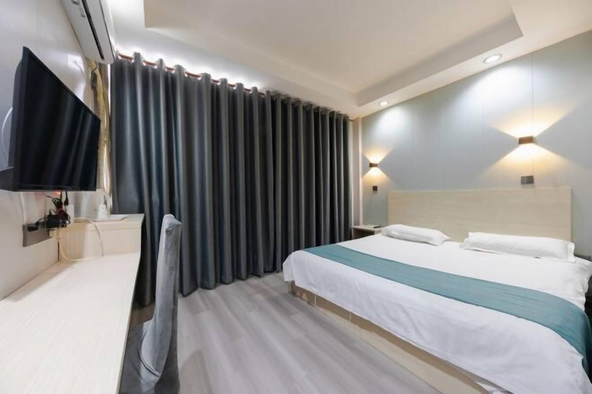 A hotel room with a bed, a TV, a desk, and a chair.