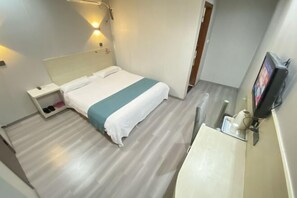 Habitación de hotel con cama, mesita de noche y televisión montada en la pared.