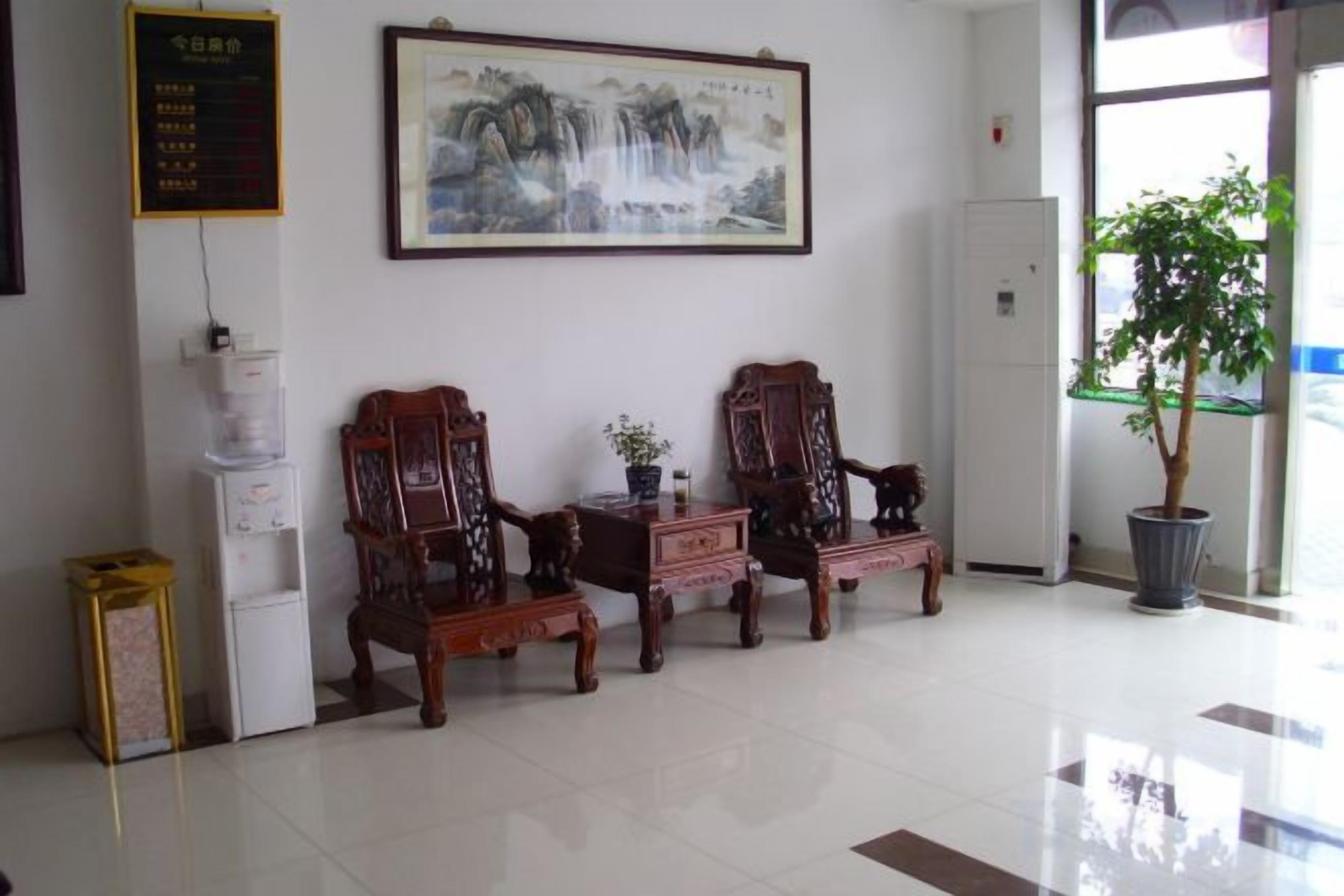 A reception area with traditional wooden chairs, a potted plant, and a wall-mounted painting.