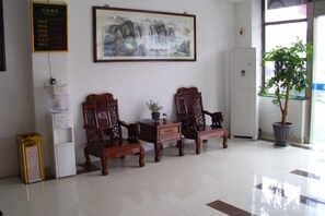 A reception area with traditional wooden chairs, a potted plant, and a wall-mounted painting. - Kuaizhilv Express Chain Hotel (Kunshan)