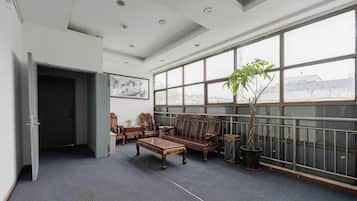 A spacious room with a large window, a sofa, a coffee table, and a potted plant.