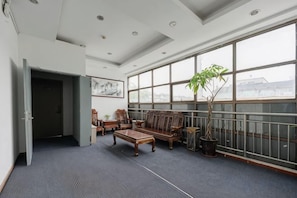 A spacious room with a large window, a sofa, a coffee table, and a potted plant. - Kuaizhilv Express Chain Hotel (Kunshan)