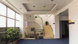 A hotel lobby with a blue carpet, a staircase, and a potted plant. - Kuaizhilv Express Chain Hotel (Kunshan)