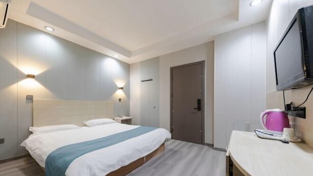 A hotel room with a bed, bedside tables, a TV, and a door. - Kuaizhilv Express Chain Hotel (Kunshan)