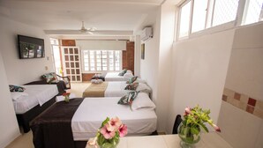 A hotel room with two single beds, a sofa, a dining table, and a ceiling fan. - HOTEL VERANO AZUL (San Andrés)