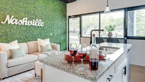 Una cocina moderna con pared verde, sofá blanco y ventana grande.