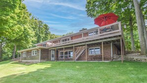 Een huis met twee verdiepingen, een balkon, een rode parasol en een stenen fundering.