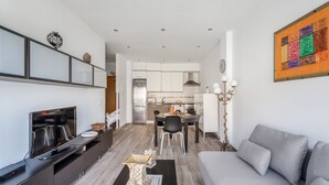 A modern living room with a flat-screen TV, a grey sofa, and a dining area with a table and chairs. - 'Casa Graham' Apartment with Sea View, Balcony and Wi-Fi (Tazacorte)