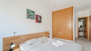 A modern bedroom with a bed, bedside lamp, artwork, and a wardrobe. - 'Casa Graham' Apartment with Sea View, Balcony and Wi-Fi (Tazacorte)