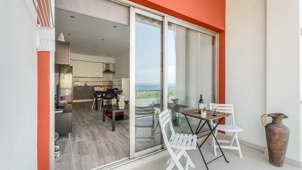 A modern kitchen with a dining area, a sliding glass door to a balcony, and a large vase on the floor. - 'Casa Graham' Apartment with Sea View, Balcony and Wi-Fi (Tazacorte)