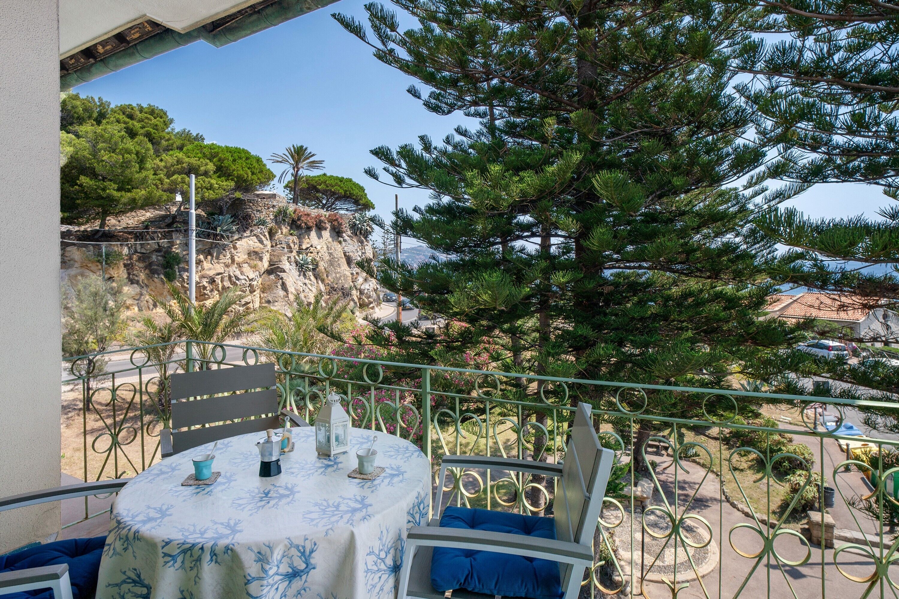 Un balcone con un tavolo apparecchiato per mangiare, affacciato su un paesaggio roccioso e un albero.