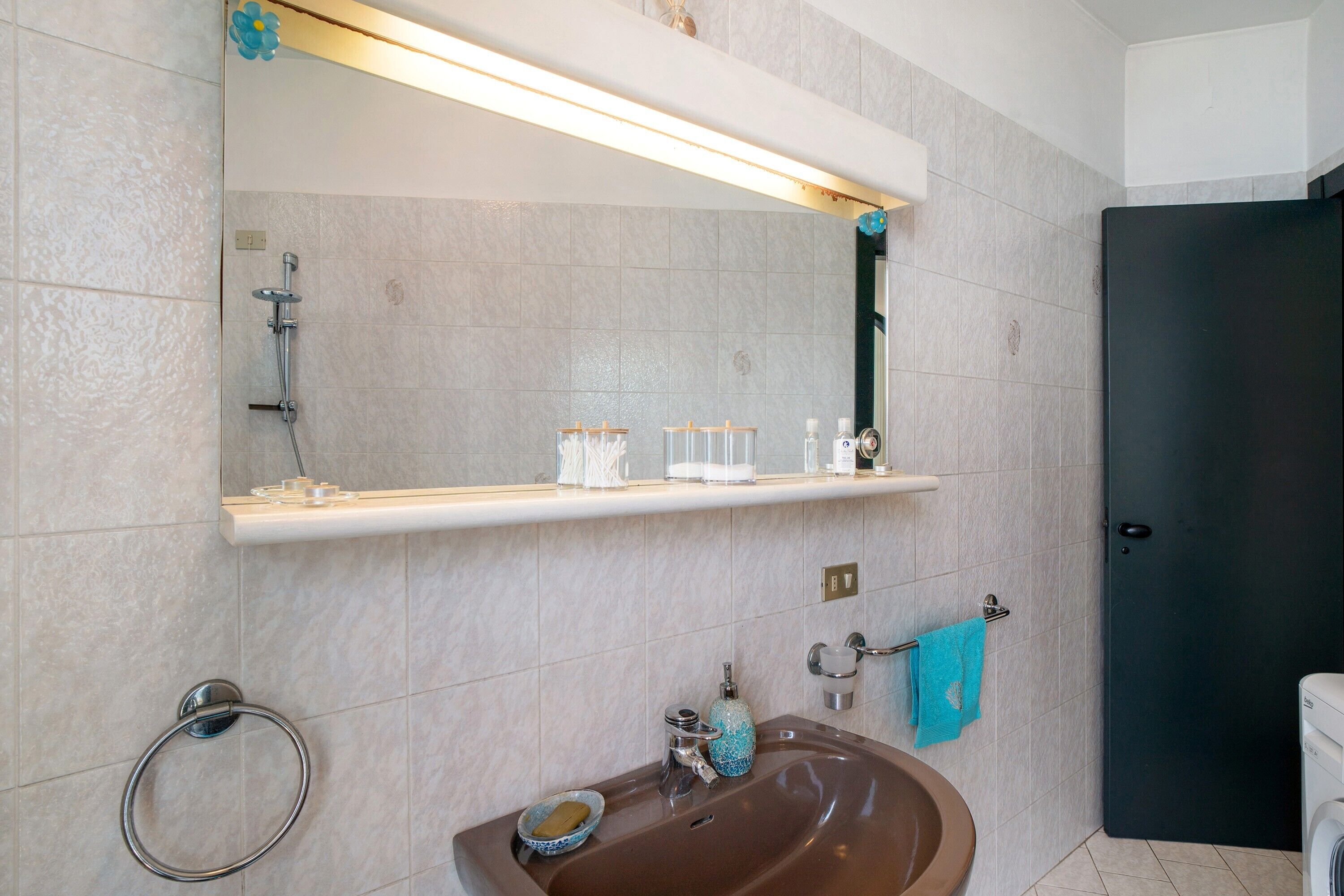 A bathroom with a sink, mirror, towel rack, and a door.