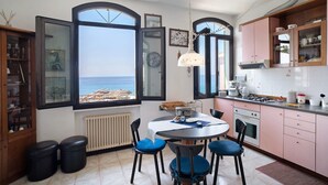 A kitchen with a view of the sea, a dining table with chairs, and a window with a view.