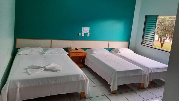 Ein Zimmer mit zwei Einzelbetten, einem Nachttisch mit Telefon und einem Fenster mit Jalousien.