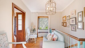 A room with a wooden floor, a white sofa, a wooden door, a chandelier, and framed pictures on the wall. - Holiday Home 'Caldera De Taburiente Rural' with Mountain View, Private Terrace and Wi-Fi (El Paso)