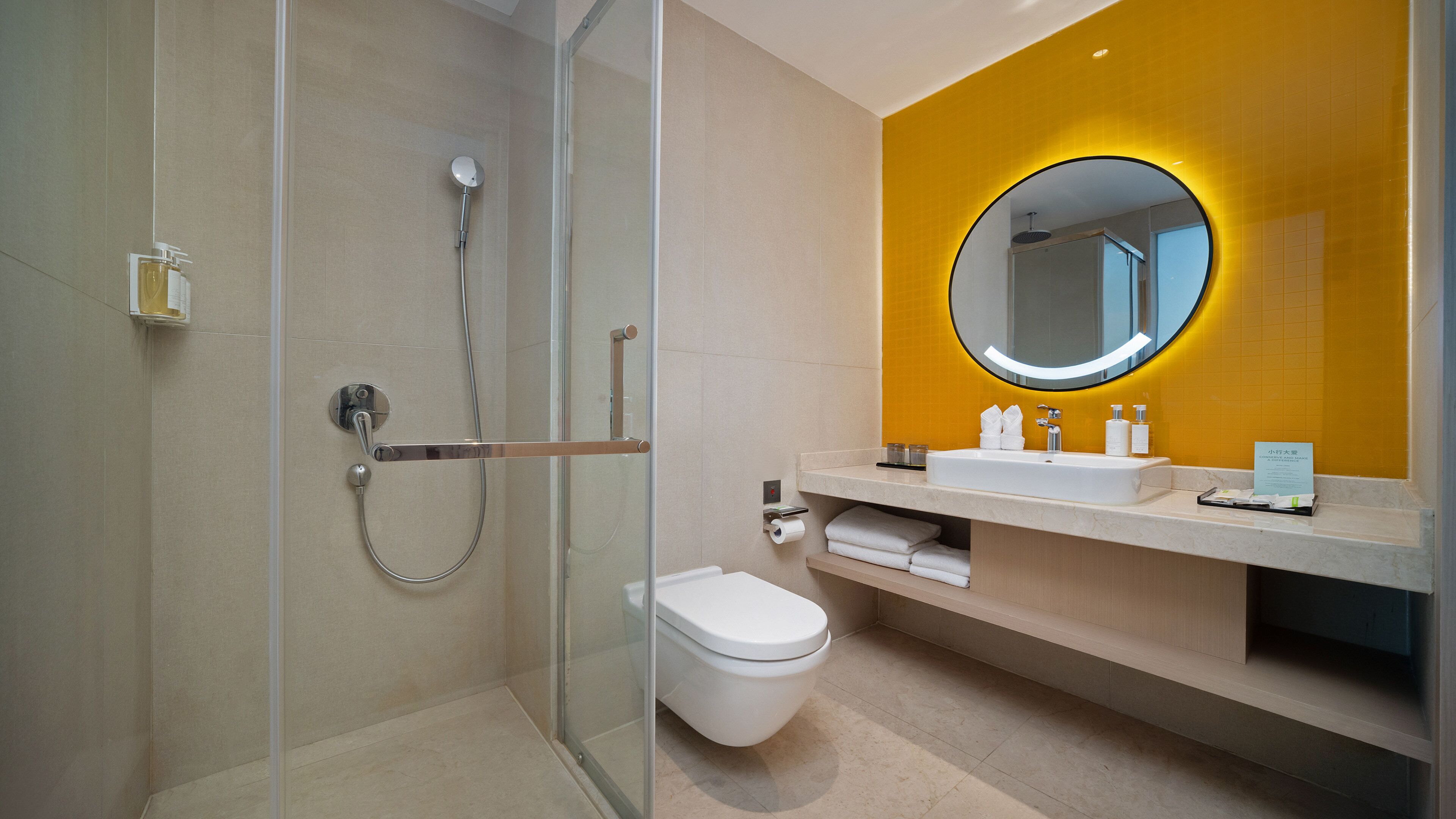 Een moderne badkamer met een douchecabine van glas, een toilet en een wastafel met spiegel.