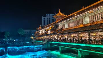 Un edificio tradicional con arquitectura ornamentada, un puente y una fuente de agua.