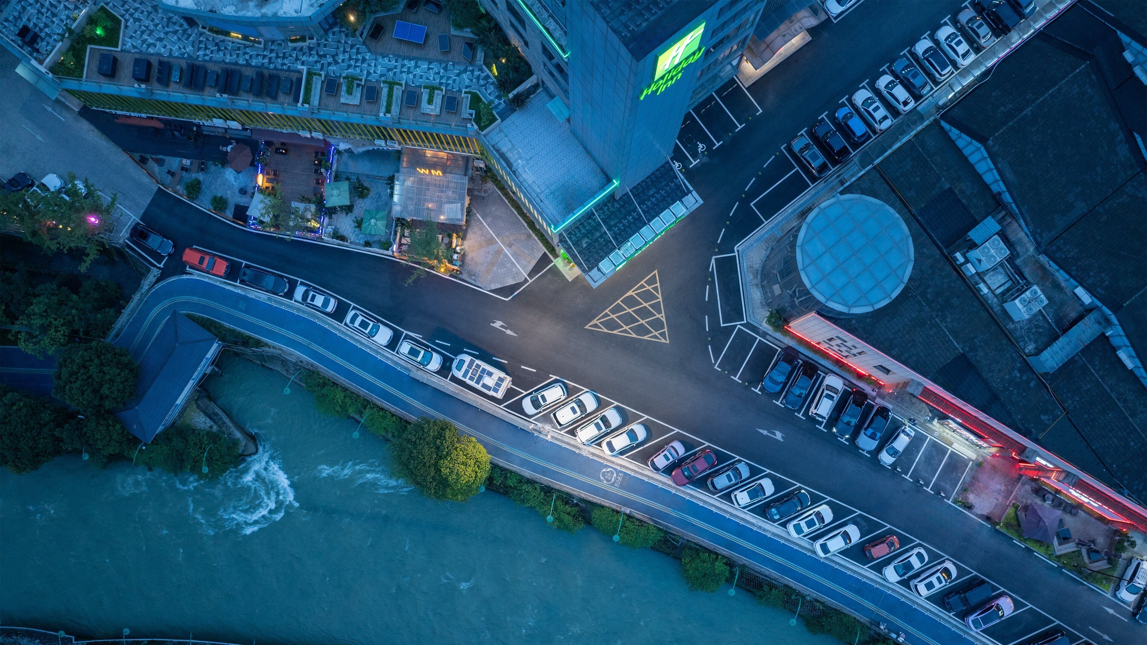 An aerial view of a modern urban area with a bridge, parking lots, and buildings.