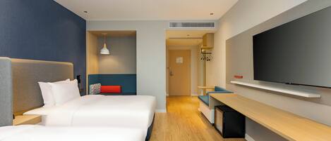 Habitación de hotel con una cama grande, un televisor en la pared y un escritorio con una silla.