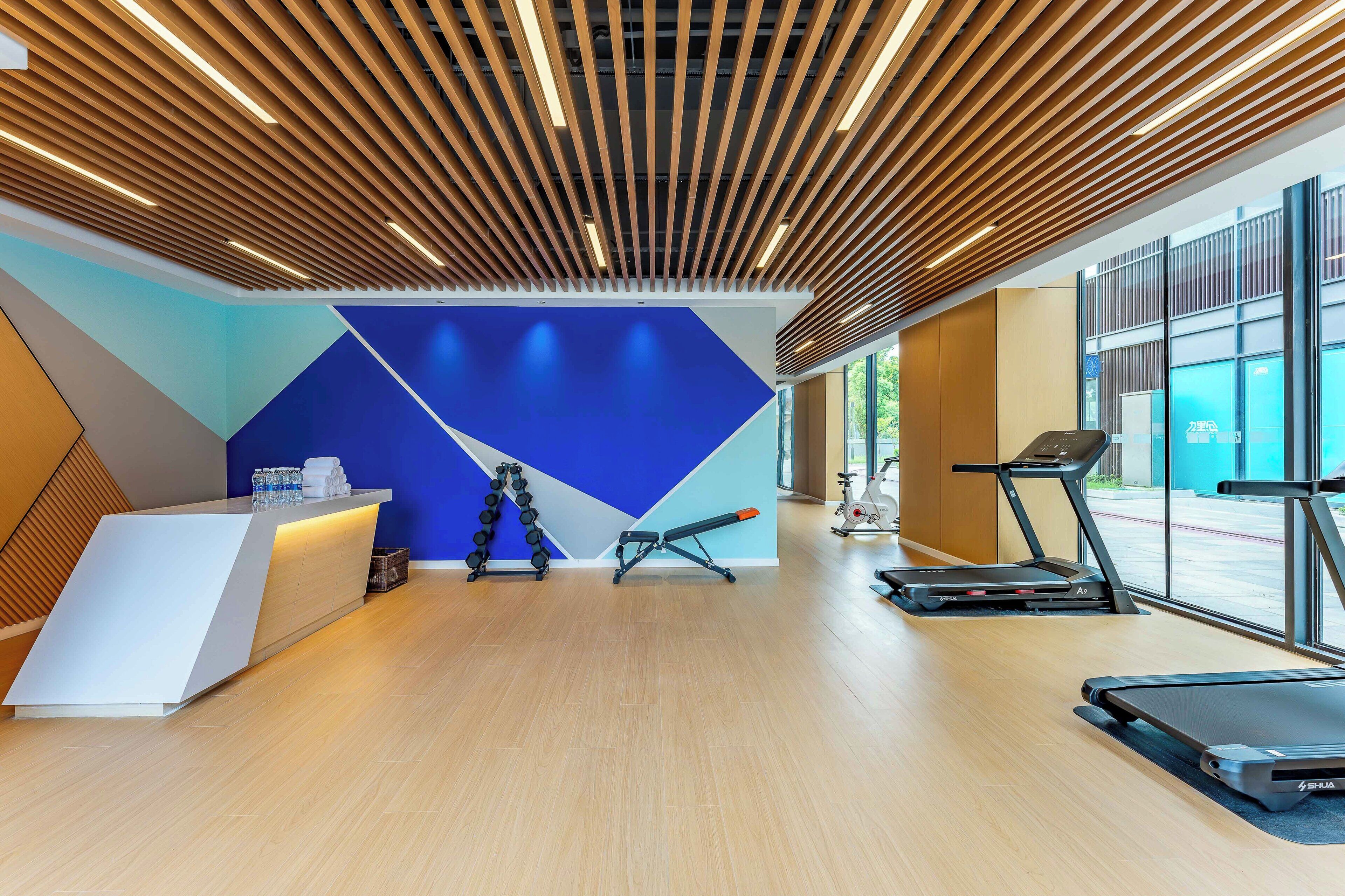 Een moderne receptie met een balie, gewichtsschijven en fitnessapparatuur.