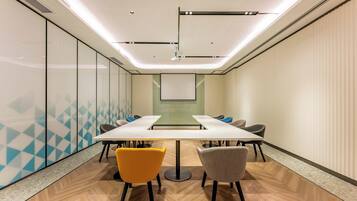 A conference room with a long table, four chairs, and a projector screen.