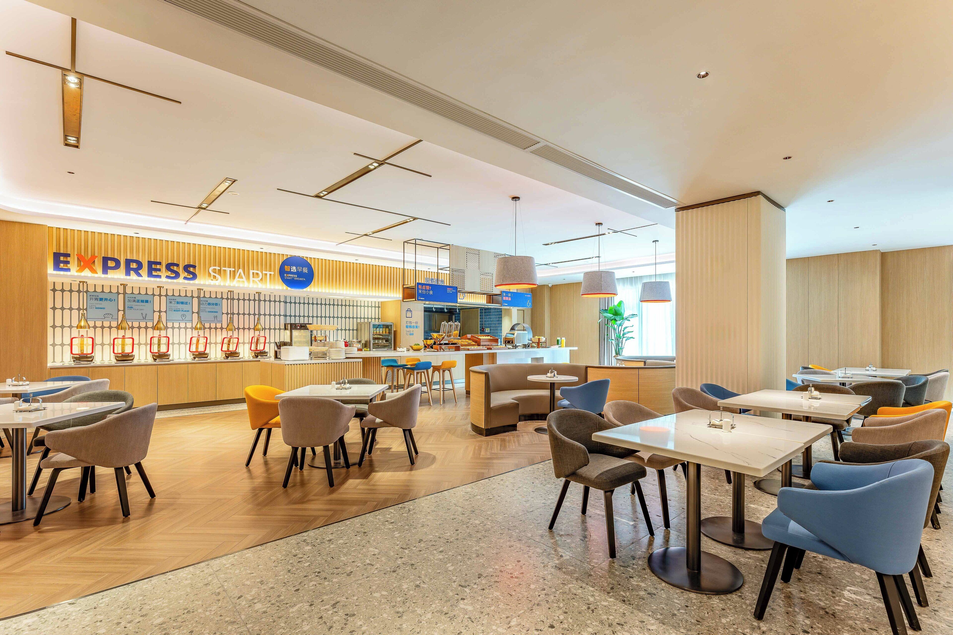 Een moderne hotellobby met een receptie, zithoekjes en een balie met het bordje 'EXPRESS START'.
