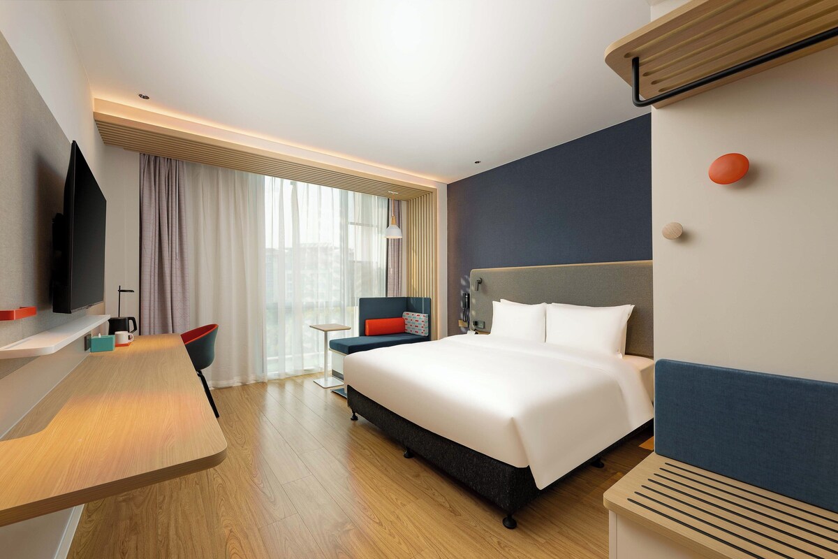 Una camera d'albergo moderna con un letto grande, una scrivania, una sedia e una televisione.