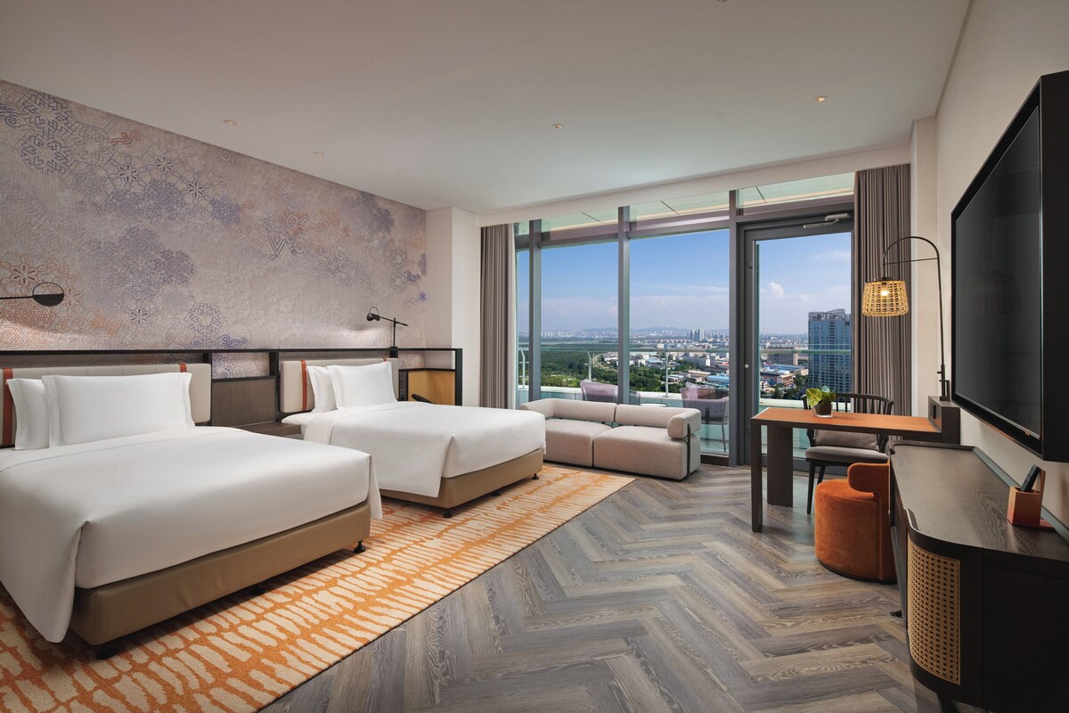 Habitación de hotel con dos camas, un sofá, una mesa de comedor y un televisor.