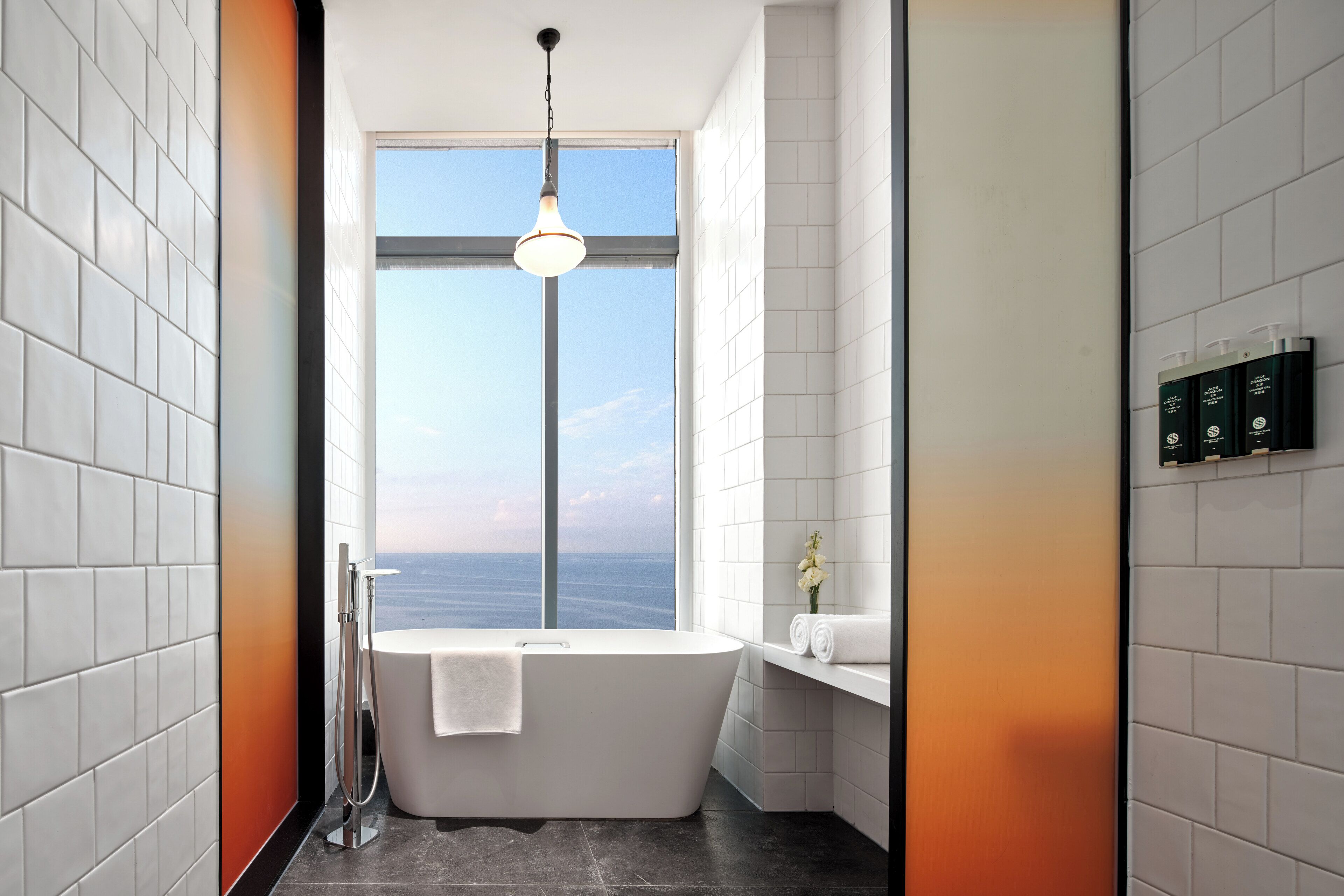 Un baño moderno con una bañera independiente, un ventanal grande y vista al mar.