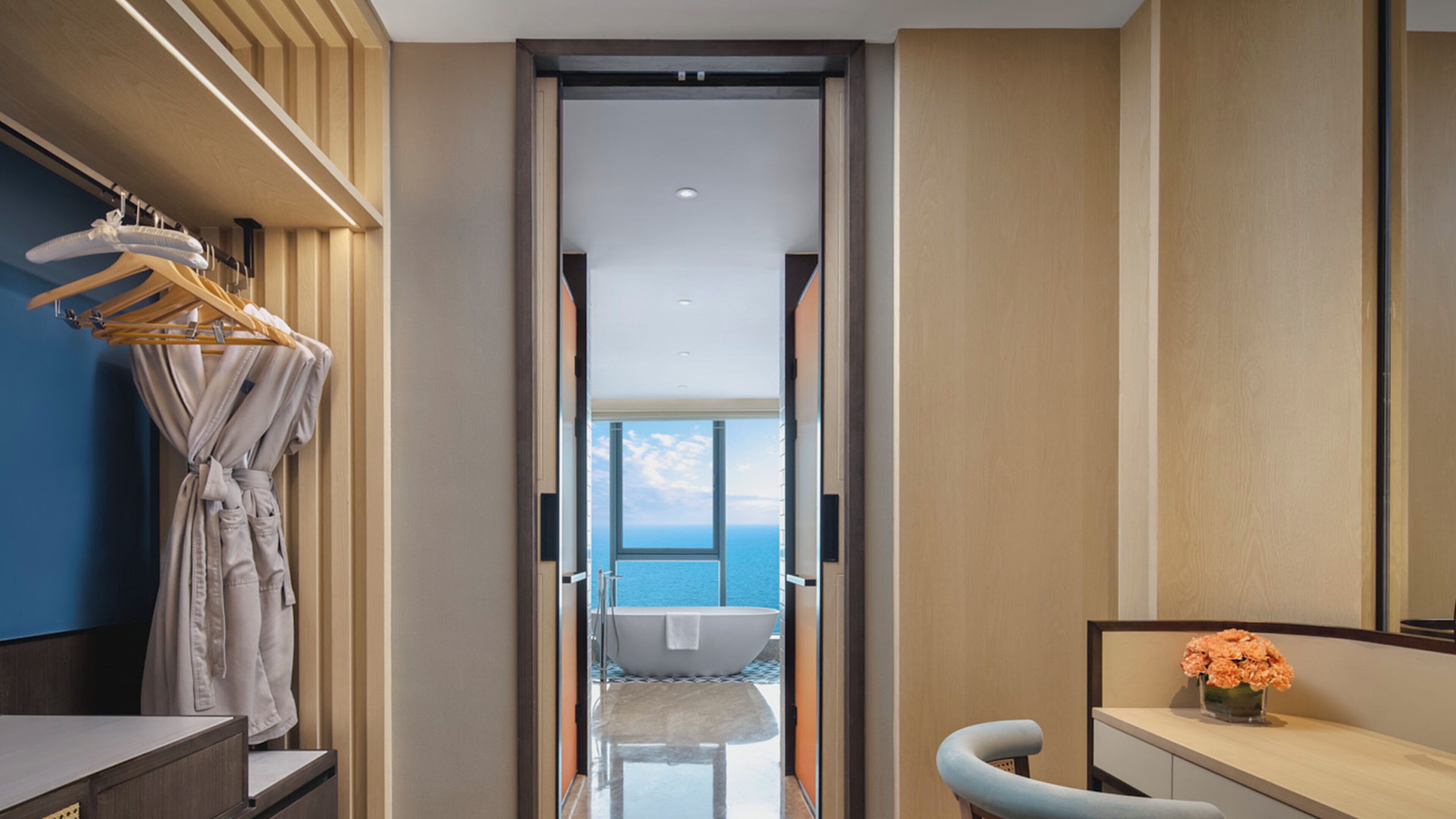 A modern bathroom with a bathtub, a vanity, and a view of the sea.