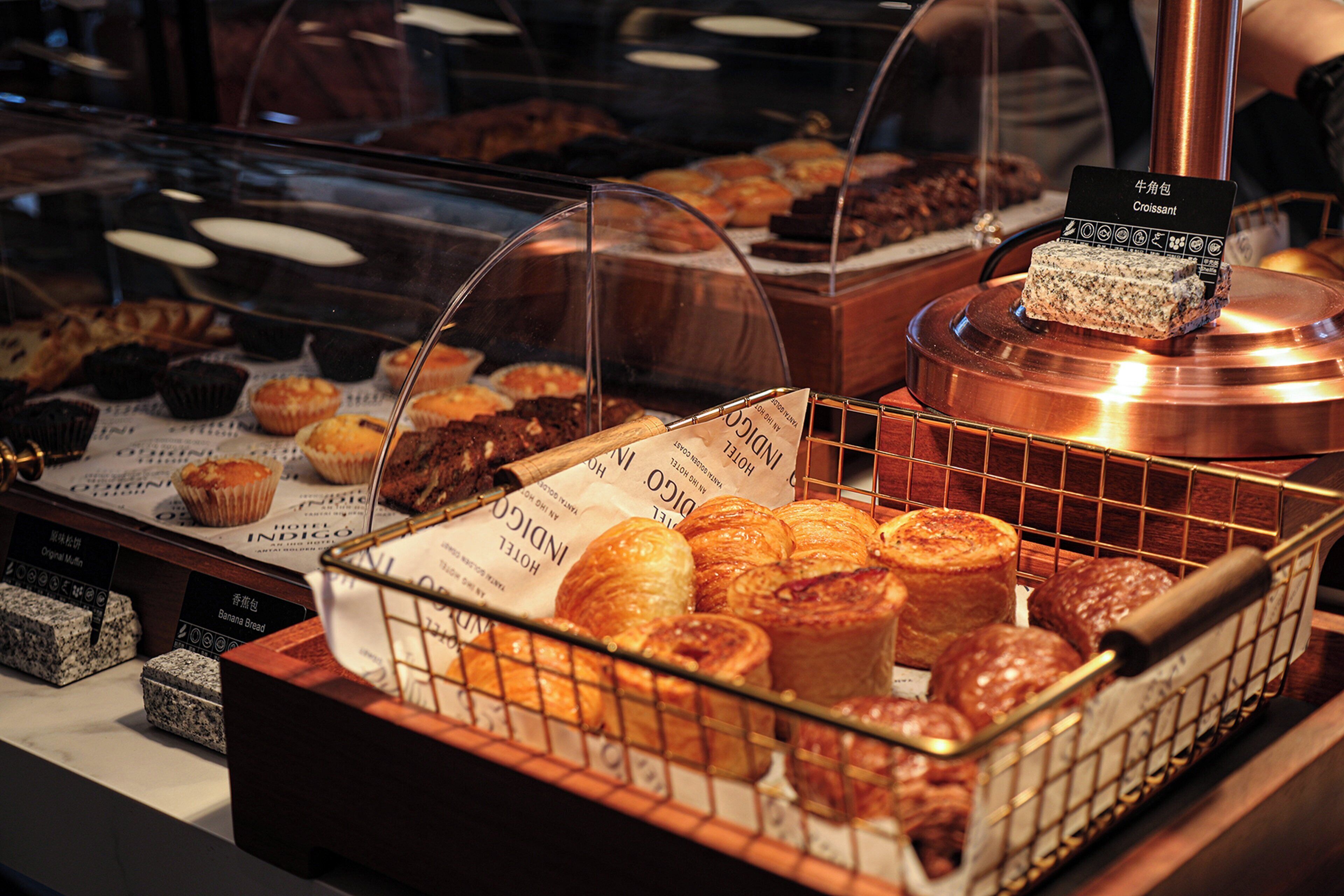 Una vetrina con diversi dolci e prodotti da forno, tra cui croissant e muffin.